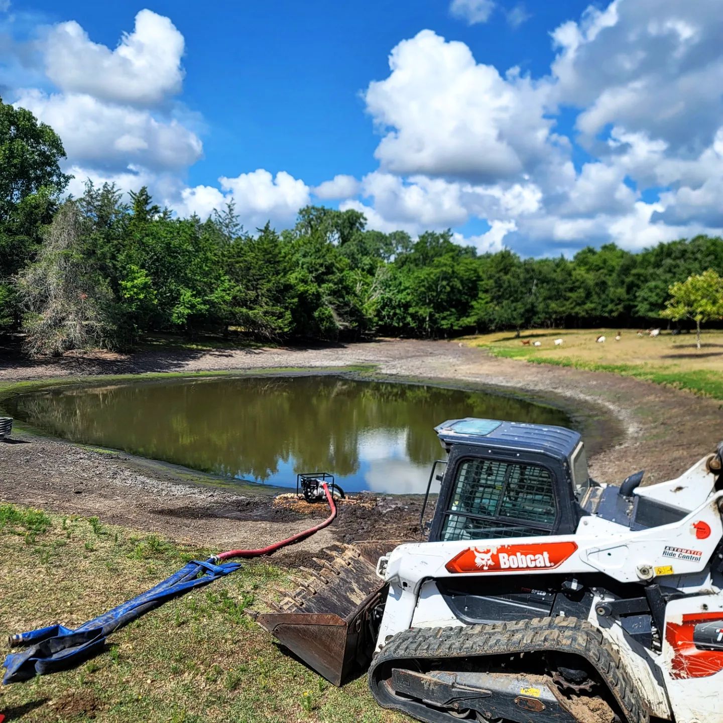 Pond in the background with a bobcat tractor in the foreground
